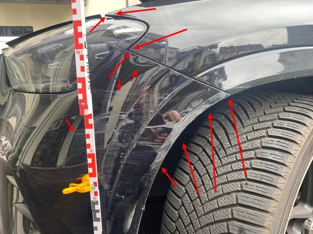 Kratzer an Kotflügel und Radlauf eines schwarzen SUV, mit Messlatte dokumentiert