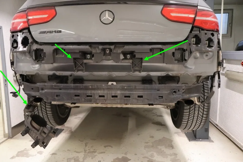 Heck desselben Fahrzeugs mit abgebautem Stoßfänger, beschädigte Halter und Träger mit Pfeilen markiert