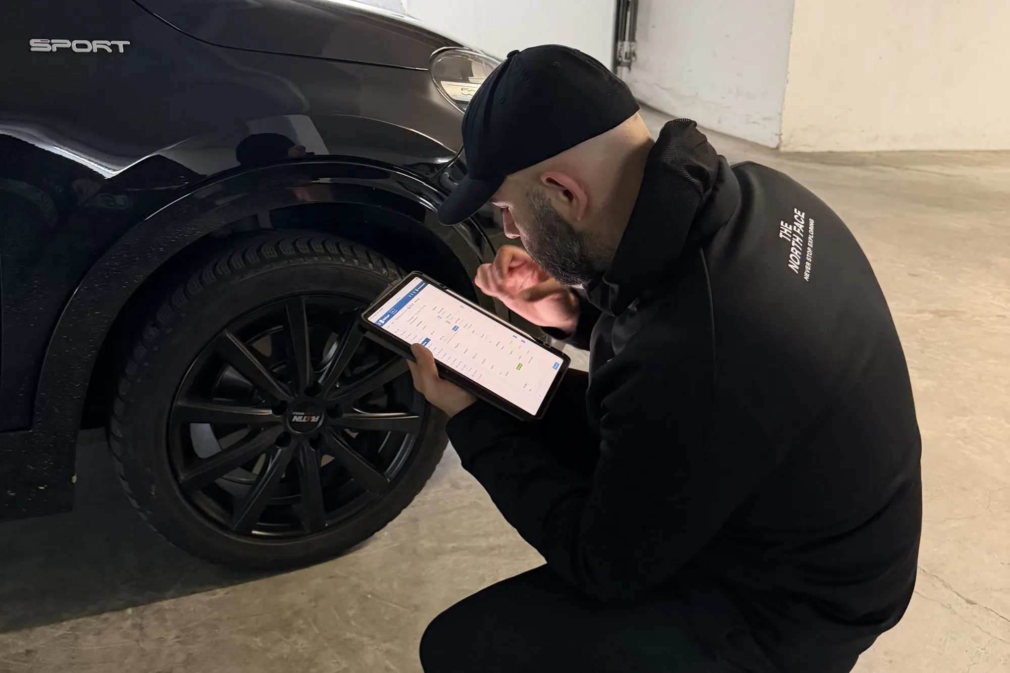 Kfz-Gutachter prüft ein Fahrzeug mit dem Tablet