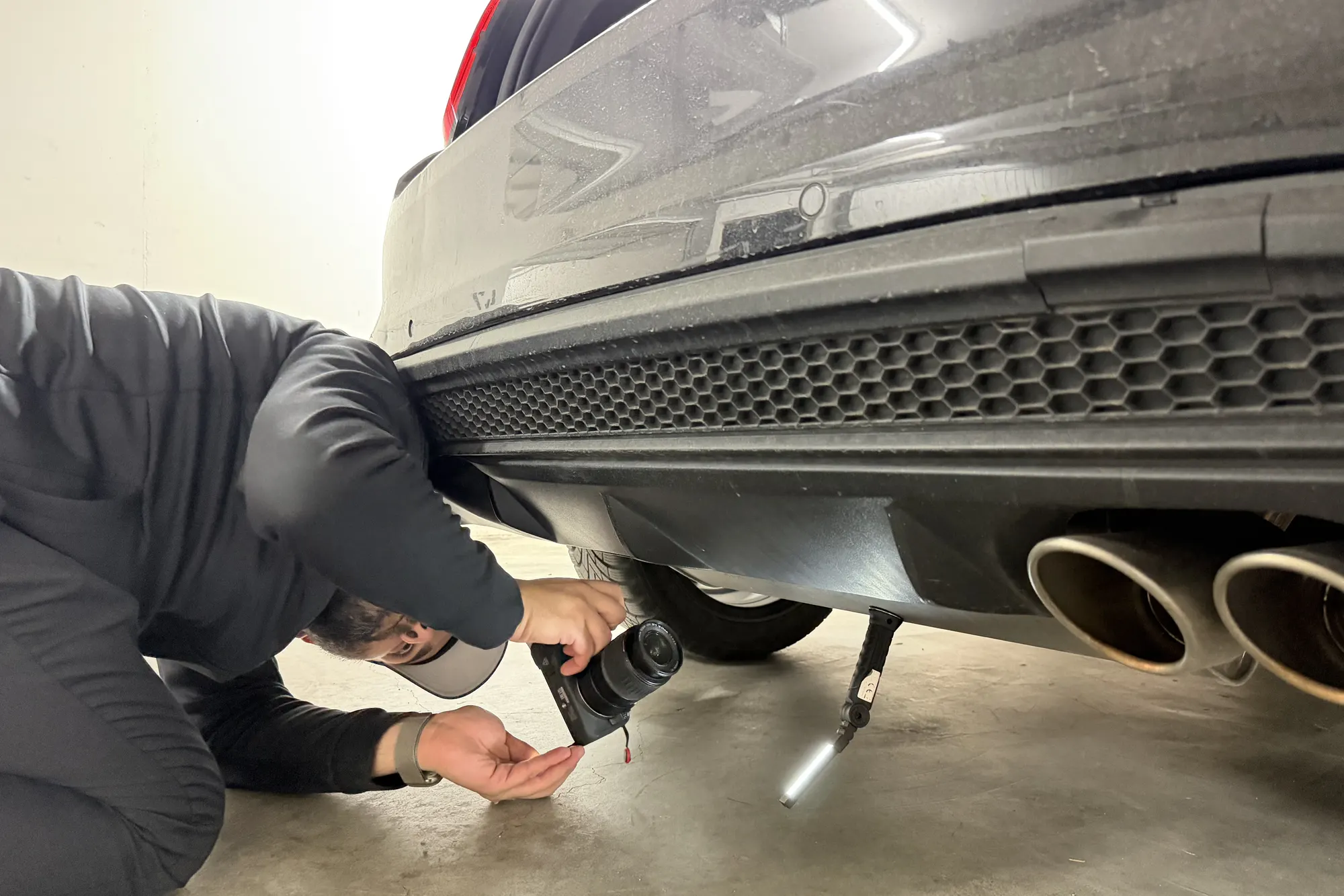 Gutachter prüft den Unterboden am Heck eines Fahrzeugs